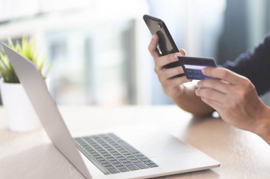 Adam mavi tişört giyer Akıllı telefon ve kredi kartı yakası olan eller