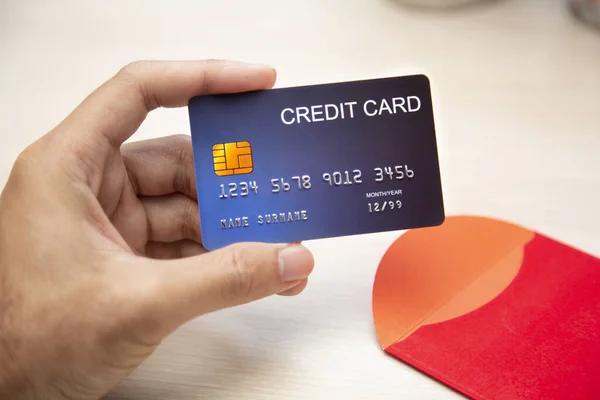 Hand Hold Cartão de Crédito e Envelope Vermelho na mesa — Fotografia de Stock