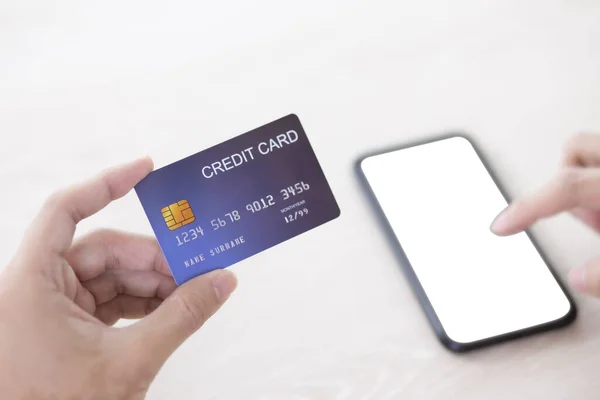Mão segurando cartão de crédito e toque smartphone defocus scre em branco — Fotografia de Stock