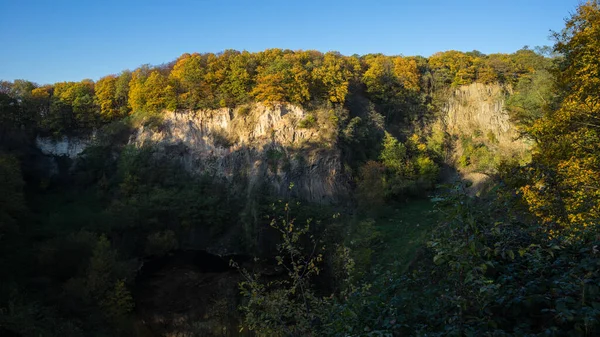 Weilbergsee 'nin kayalık duvarının panoramik manzarası ve akşam ışığında sonbahar ormanı..