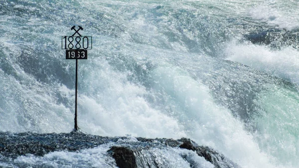 Sign 1880 in the middle of the roaring waters of the Rhine Falls.