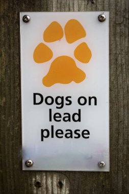 Kırsal bir çitin işareti tüm köpeklerin bir yol göstericide tutulması gerektiğini belirtiyor.