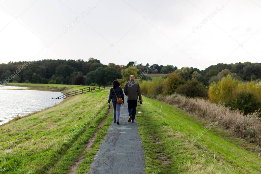 A middle aged couple taking their dog for a walk through the countryside