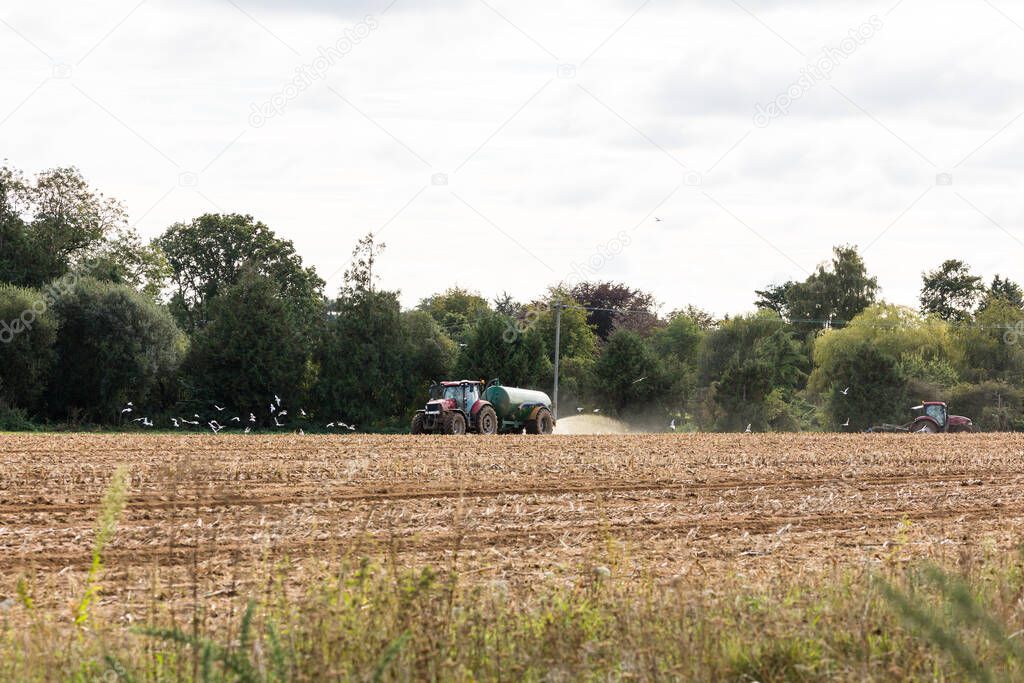 A tractor spreading slurry, fertilizer on the field ready to plant new crop