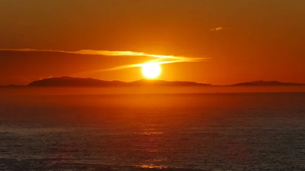 Puesta de sol en la costa del Cantábrico con montañas y niebla — Foto de Stock