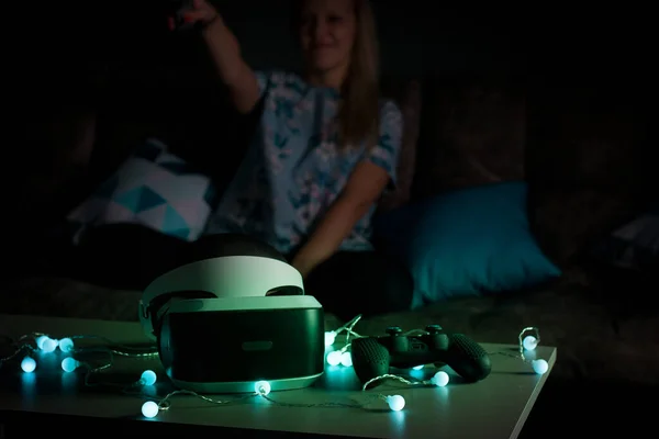 VR virtual reality. Girl wants to get experience using glasses of a VR headset. Amazing emotions, cool rest, reboot. Virtual reality glasses lie in neon lights. Concept of visual reality