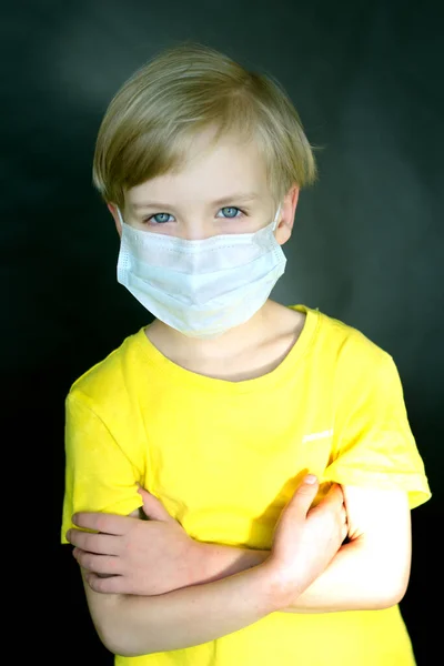 Criança em uma máscara médica com um urso de brinquedo em seus braços em um fundo preto. O jogo do médico. O conceito de proteção contra vírus e doenças. Parem o coronovírus. Covid-19 — Fotografia de Stock