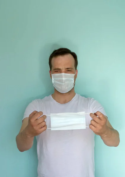 Retrato de un hombre atractivo con una máscara médica y un guante sobre fondo azul. Concepto de Protección Pandémica. Detén el coronovirus. Covid-19 — Foto de Stock