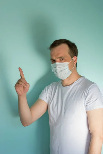 Retrato de un hombre atractivo con una máscara médica y un guante sobre fondo azul. Concepto de Protección Pandémica. Detén el coronovirus. Covid-19 — Foto de Stock