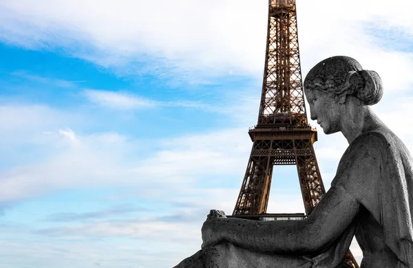 Эйфелева башня в Париже в объятиях статуи сидящей женщины — стоковое фото