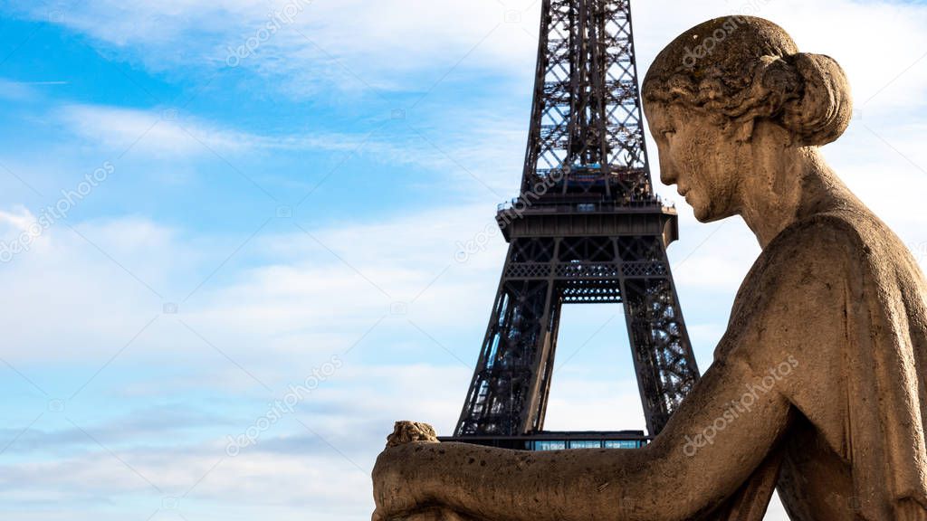 The Eiffel Tower in Paris in the arms of a statue of a seated woman