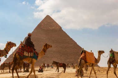 Giza, Mısır - 29 Ocak 2020 - Develerle ve piramidin önündeki insanlarla dolu bir turizm