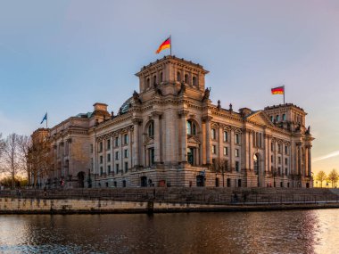Alman Parlamentosu Reichstag Binası bahar akşamının batımında. Spree Nehri 'nin diğer kıyısından görüntüle.