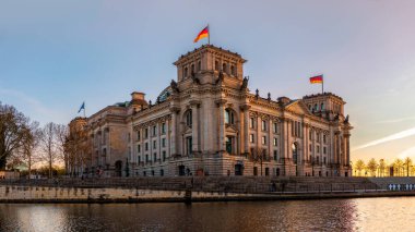 Alman Parlamentosu Reichstag Binası bahar akşamının batımında. Spree Nehri 'nin diğer kıyısından görüntüle.