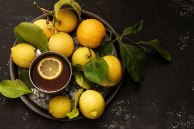 Taze limonlar ve koyu arkaplanda bir fincan çay.