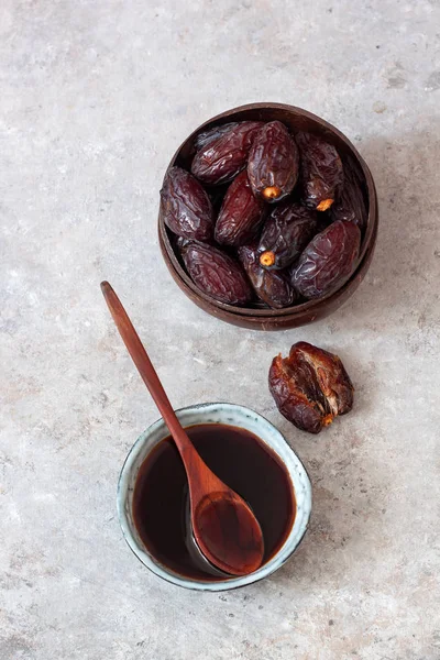 Natural date syrup in a bowl with whole dates in the background