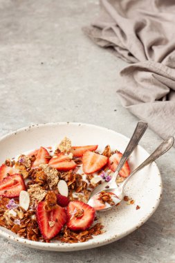 Yoğurtlu lezzetli kahvaltı, böğürtlen ve granola gri masada.