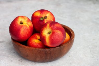 Tahta bir kasede taze nektarinler.