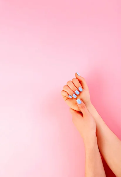 Manos de una hermosa mujer sobre un fondo rosa. Clavos azul claro . — Foto de Stock