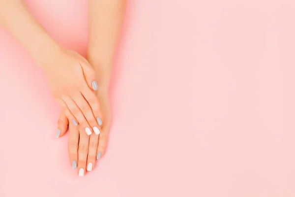 Hermosa mano de mujer joven con perfecta manicura gris sobre fondo rosa . — Foto de Stock