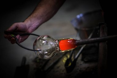 Cam üfleyici güzel bir cam parçası oluşturuyor. Bir cam ustası bir sanat eserini yakıyor ve üflüyor. Cam üfleyici ürününü dikkatlice üretiyor. Cam üfleme işlemi