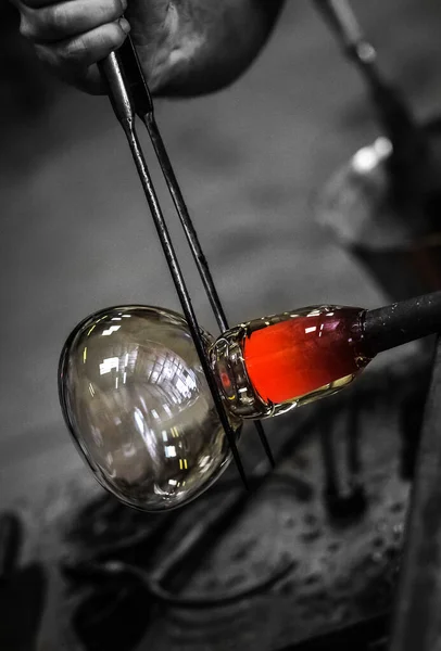 玻璃鼓风机形成漂亮的玻璃片 一个玻璃工匠正在燃烧和吹一个艺术品 玻璃鼓风机小心地制造他的产品 玻璃吹风工艺 — 图库照片