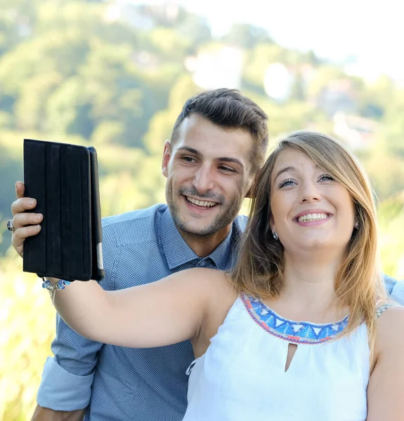 Szczęśliwa Para Młodych Studentów Korzystających Tabletu Cyfrowego Telefonu Komórkowego Słuchawkami — Zdjęcie stockowe