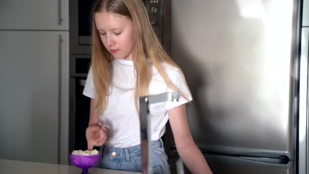 Teenager girl tastes whipped cream dessert at the kitchen — Stock Video