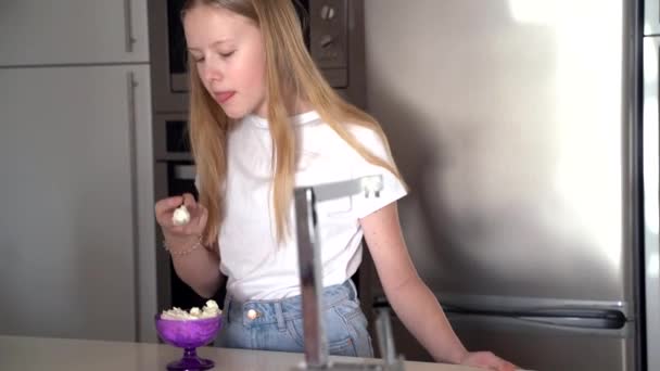Genç kız mutfakta kremalı tatlıyı tadıyor. — Stok video