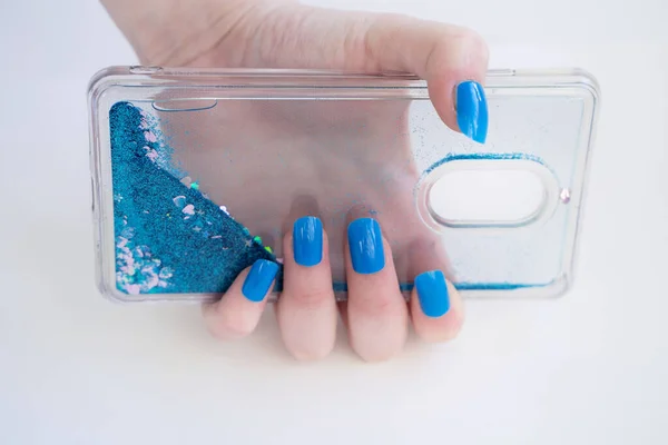 Hands with blue acryl nail holding glamour cover of phone — Stockfoto