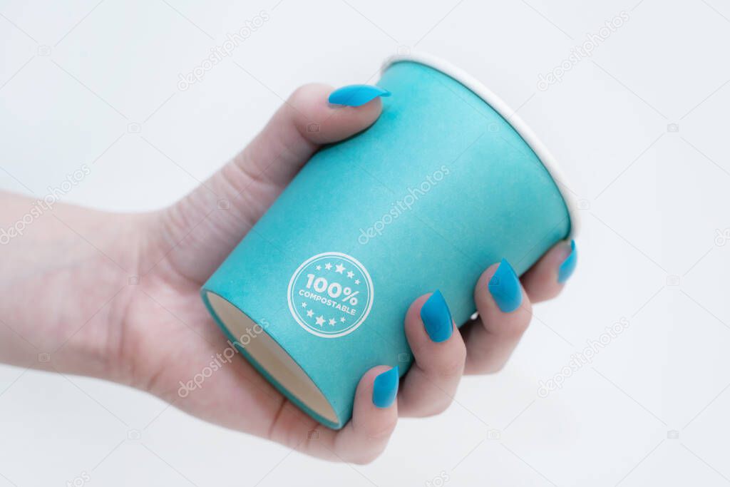 women hand holds the paper cup recyclable in blue on a white background. ecological concept