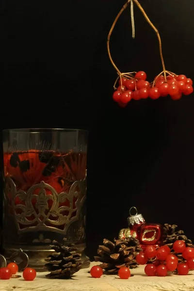 Tea with red berries in a glass and Christmas decoration — Stock Photo, Image