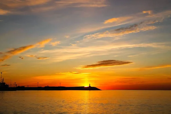 Sunrise in Malaga, Spain. Lighthouse on the horizon — Stock Photo, Image