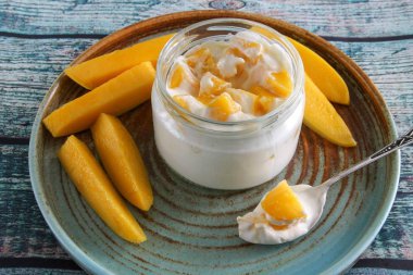 Cam şeffaf bir kavanozda doğal yoğurtla dilimlenmiş sarı mango..