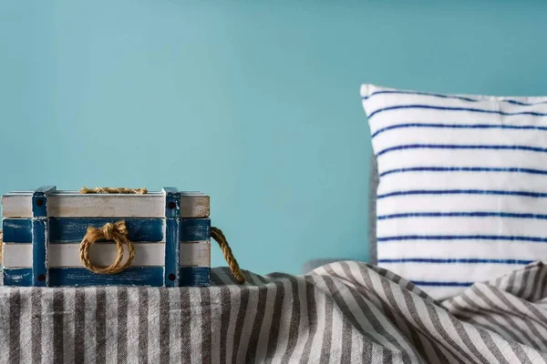 Marine style in the interior of the apartment - a sofa with pillows and the striped casket. Blue room marine concept.