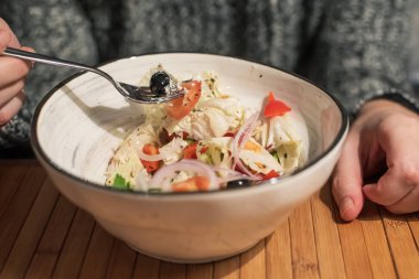 Çatallı erkek eller ve beyaz kasede taze sebze salatası.