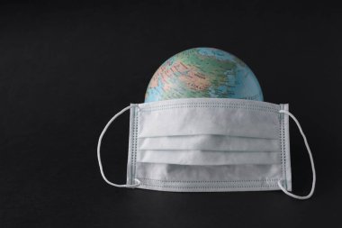 Coronavirus konsepti. Dünya ve maske Corona virüsüyle savaşmak için. Virüs saldırısı siyah arkaplanda izole edildi.