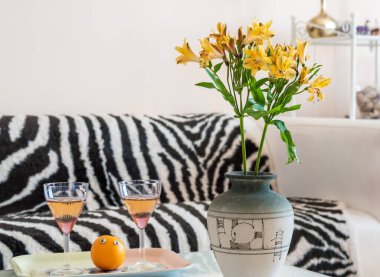 Vazoda Alstroemeria çiçekleri ve masada iki şarap bardağı.