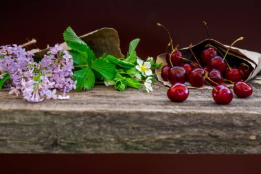 Kiraz ve çiçekler ahşap bir el sanatları masasında.