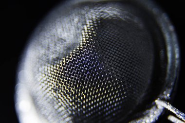 a tea strainer in close-up against black background clipart