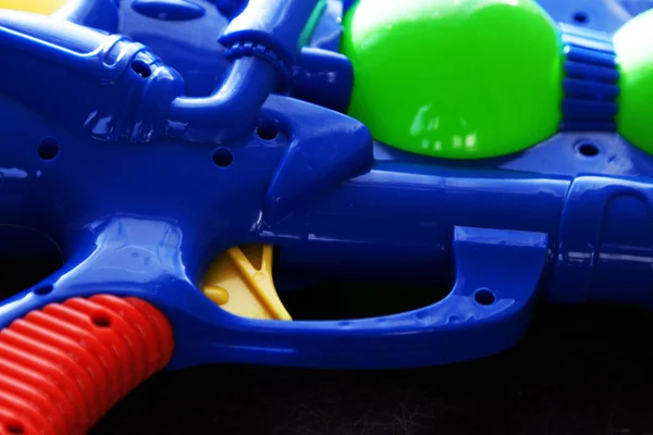 Gatillo para una pistola de agua de plástico azul acostado sobre fondo oscuro — Foto de Stock