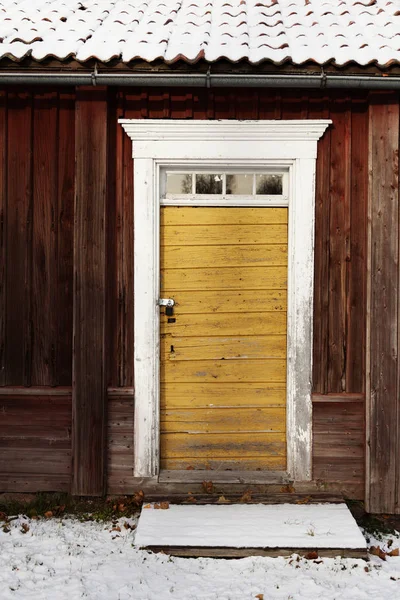 Stare zużyte żółte drewniane drzwi do równie starego domu — Zdjęcie stockowe