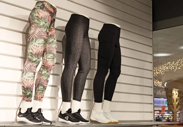 Tres pantalones de entrenamiento en piernas femeninas en tienda de artículos deportivos — Foto de Stock