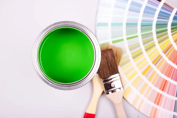 Pincel de pintura que pone en un montón de muestras de color. lata abierta de pintura verde —  Fotos de Stock