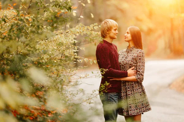 Coppia indossato in maglioni vestiti in stile autunno sguardo familiare che corre attraverso il paesaggio autunnale. Foresta ricoperta di fogliame giallo. Autunno a piedi all'aperto . — Foto Stock