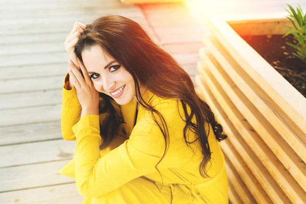 Молода приваблива жінка біля моря в літній або осінній день. сидячи на набережній в жовтій сукні. стильний вигляд — стокове фото