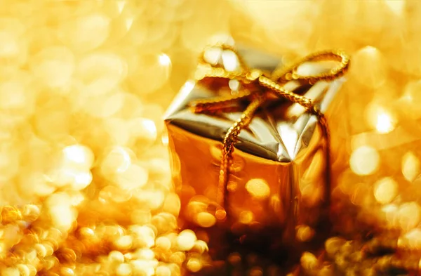 Złoty prezent na rozproszone światła tło zbliżenie — Zdjęcie stockowe