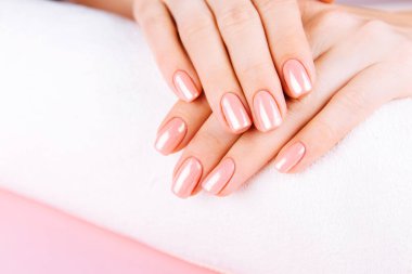 Güzel Kadın Elleri. Spa ve Manikür konsepti. Pembe manikürlü kadın elleri. Yumuşak cilt konsepti. Güzel tırnaklar. Bej arkaplanda.