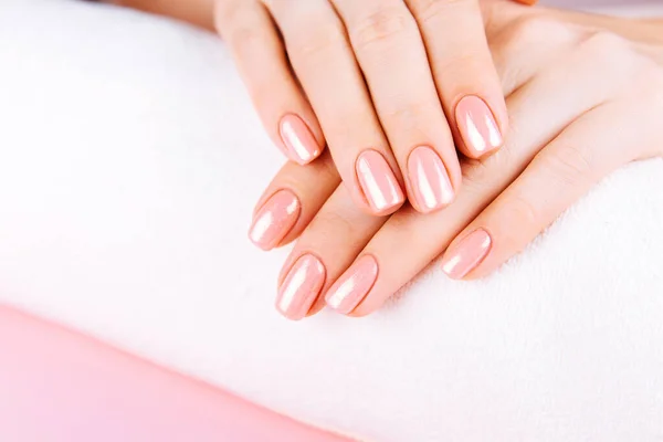 Hermosas manos de mujer. Concepto de spa y manicura. Manos femeninas con manicura rosa. Concepto de cuidado de la piel suave. Clavos de belleza. Sobre fondo beige . — Foto de Stock