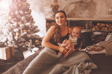 gülümseyen anne Noel ağacının yakınında güzel bebek ile oynarken.